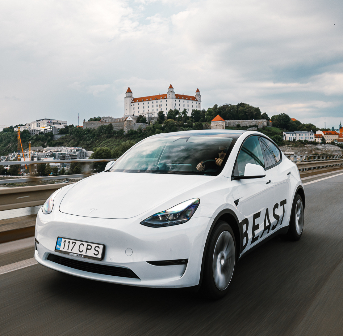A man happily driving a rented Tesla from Beast Rent, showcasing our premium electric car rental service for awesome travel experiences. Enjoy the luxury and convenience of free international travel in Europe with Beast Rent's high-quality Tesla rental.